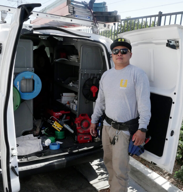 An electrician stands by his service van, fully equipped with tools and supplies, ready to provide professional electrical repair and maintenance services.