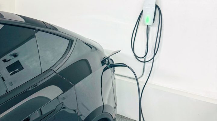 A home electric vehicle charging station installed in a garage, showing a plugged-in charger with a sleek and modern design for efficient vehicle charging.