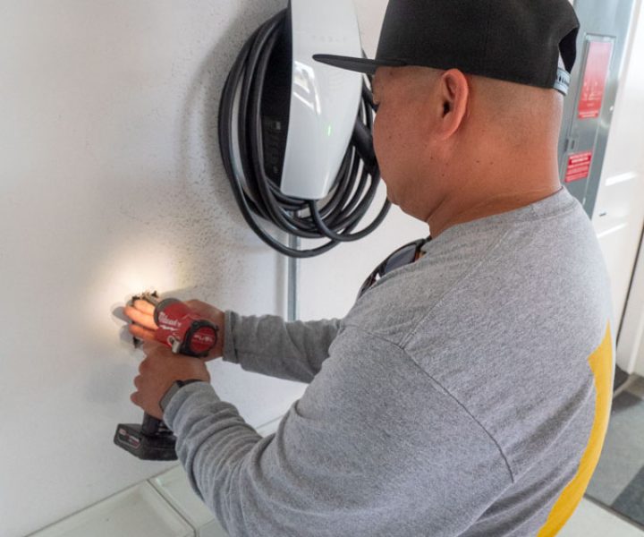 An electrician works on setting up an EV charger in a residential garage, focusing on delivering reliable and safe electrical services.